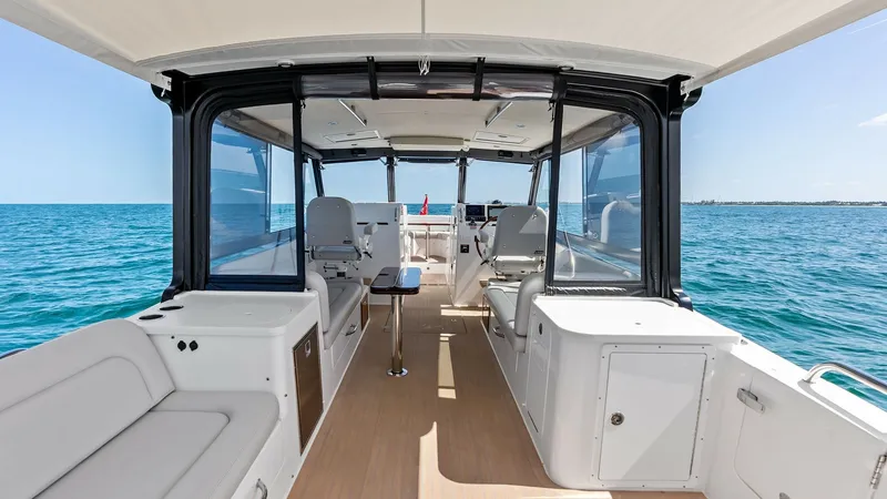 Slide: The Image of Spacious Cockpit with Seating The Sunshine Crew's cockpit offers a spacious and inviting area for relaxation and entertainment. Featuring comfortable upholstered seating and a sleek, modern design, this area is perfect for enjoying panoramic ocean views. The teak flooring adds a touch - 6834906