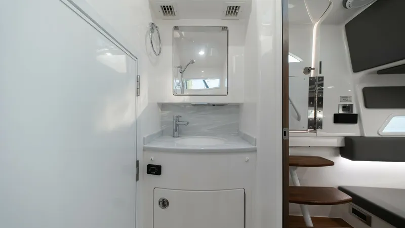 Slide: The Image of Compact Head with Vanity This sleek and modern head features a refined vanity with a polished sink and contemporary fixtures, providing both style and functionality. The cabinetry offers ample storage while the overhead lighting ensures a bright and inviting space. Adjacent seati - 7162311