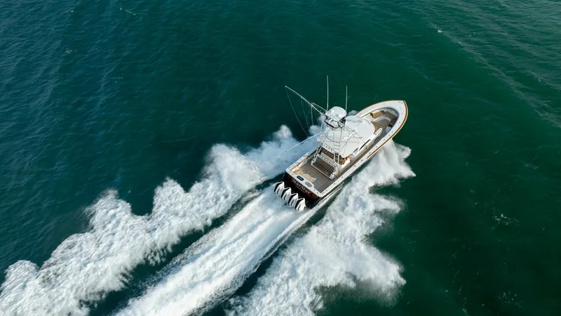 Slide: The Image of Aerial View of V-46 in Motion This aerial shot captures the Valhalla Boatworks V-46 cruising powerfully through open waters. The vessel's sleek design and robust quad-engine setup are prominently featured, demonstrating its impressive speed and agility. With a spacious deck and comman - 7162336