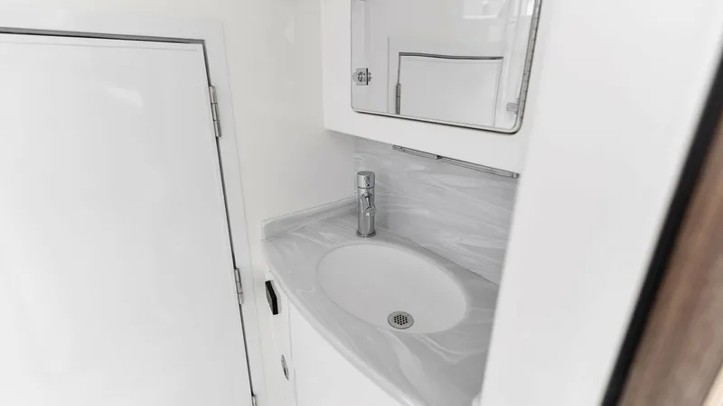 Slide: The Image of Compact Yacht Bathroom Vanity This image showcases the sleek and modern vanity area within the MarMar's bathroom. The clean, high-gloss cabinetry complements the smooth, marble-patterned countertop, creating a sophisticated look. A contemporary faucet and integrated sink add functiona - 6845081