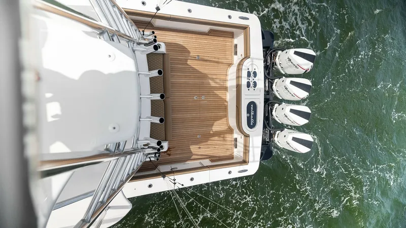 Slide: The Image of Aerial View of Aft Deck and Engines This aerial perspective showcases the spacious aft deck of the Valhalla Boatworks V-46, featuring elegant teak flooring. The image highlights the powerful quad outboard engines, ensuring top-tier performance and handling. The deck's clean lines and ample - 6845077