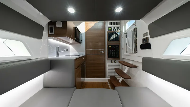 Slide: The Image of Modern Galley and Seating Area The interior of the MarMar V-46 showcases a sleek galley with contemporary finishes, featuring a polished sink and ample cabinetry. The adjacent seating area is upholstered in soft gray, providing a comfortable and stylish space for relaxation. Recessed l - 7162308
