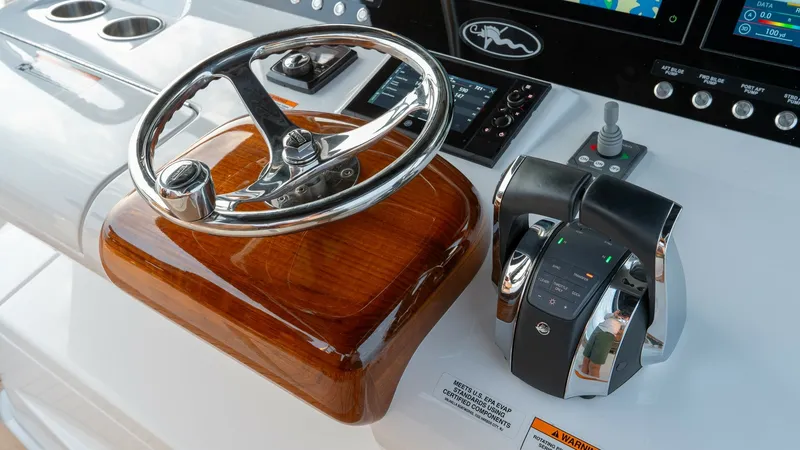 Slide: The Image of Helm Station with Electronics The helm station of the 2022 Valhalla V-46 features a sleek stainless steel steering wheel mounted on a polished wood base, exuding luxury and precision. Modern electronic controls and a state-of-the-art navigation display provide the captain with intuiti - 7162287