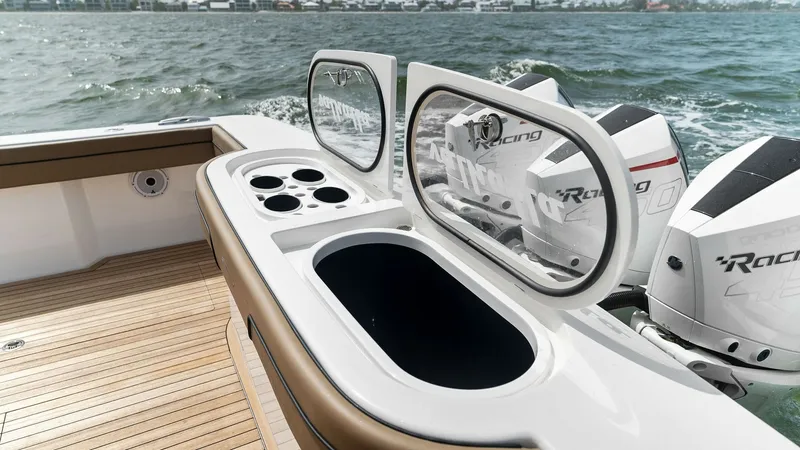 Slide: The Image of Aft Deck with Livewell and Engines The aft deck features a sleek livewell and bait prep station, ideal for fishing enthusiasts. Surrounded by a finely crafted teak deck, it offers easy access to twin high-performance engines, ensuring superior speed and handling. The arrangement balances f - 6845074
