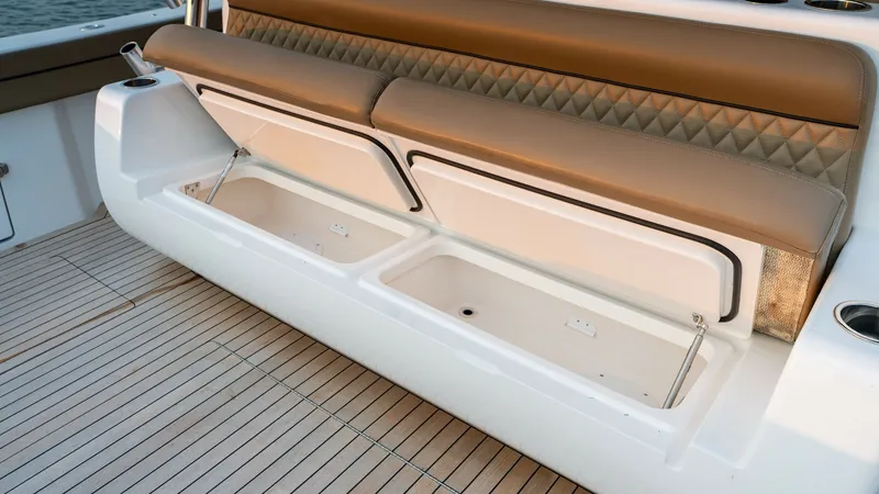 Slide: The Image of Aft Deck Seating with Storage This image showcases the aft deck seating of the 2022 Valhalla Boatworks V-46, featuring a plush, tan cushion with diamond stitching for added elegance. Beneath the seating, spacious storage compartments are revealed, perfect for stowing gear or personal - 7162298