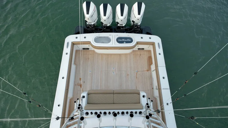 Slide: The Image of Spacious Aft Deck with Quad Engines This image showcases the expansive aft deck of the Valhalla Boatworks V-46, featuring a sleek, teak-finished floor. The deck is complemented by a comfortable bench seat and is equipped with state-of-the-art quad outboard engines for optimal performance. I - 7162306