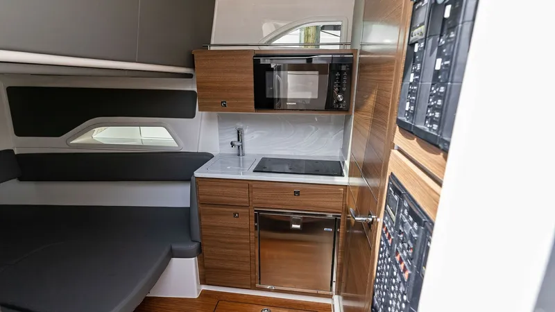 Slide: The Image of Modern Galley with Integrated Appliances This sleek galley on the 2022 Valhalla V-46 features modern cabinetry and high-end appliances, including a microwave and an induction cooktop. The compact layout maximizes space efficiency, while the wood finish adds a touch of elegance. Ample counter spa - 6845080