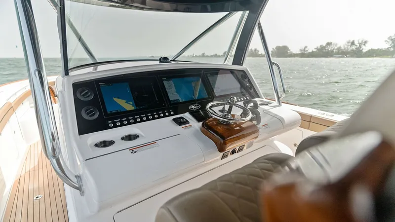 Slide: The Image of Helm Station with Electronics Display The helm station of the 2022 Valhalla Boatworks V-46 features a sleek, modern design equipped with advanced navigation electronics. A polished wood steering wheel complements the digital displays, providing both functionality and elegance. The ergonomic s - 6845067