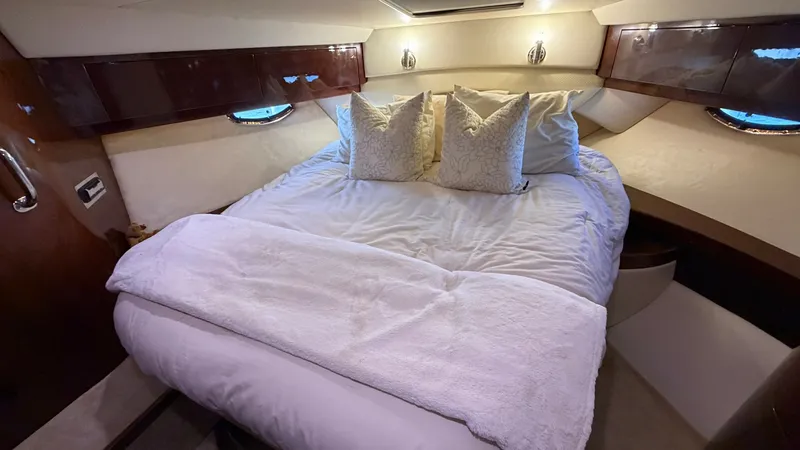 Slide: The Image of Forward Stateroom with Queen Bed The forward stateroom of the 2014 Regal 46 Sport Coupe offers a luxurious queen-sized bed adorned with plush bedding and decorative pillows. Rich wood finishes complement the soft ambient lighting, creating a cozy and inviting atmosphere. Ample storage an - 6857434