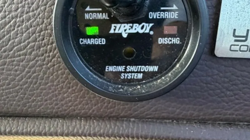 Slide: The Image of Engine Shutdown Control Panel This image showcases the Fireboy engine shutdown system on the 2014 Regal 46 Sport Coupe. The panel features indicators for normal and override modes, with a clear display of the charged status. The leather-like finish surrounding the panel adds a touch o - 6857454