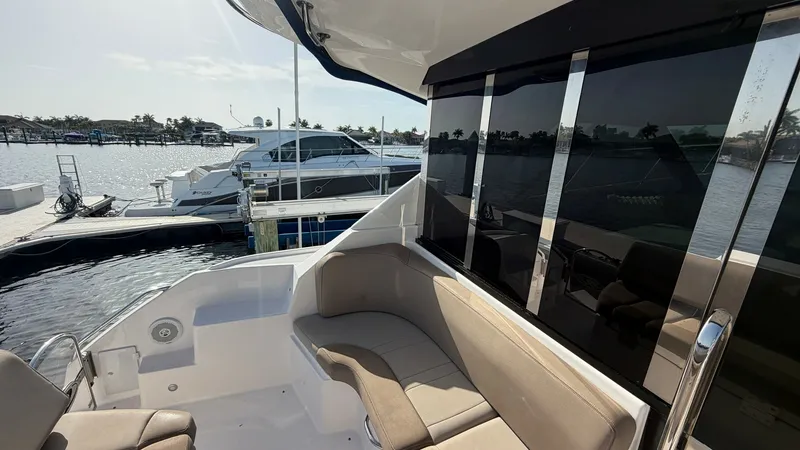 Slide: The Image of Aft Deck Seating Area The aft deck of the Regal 46 Sport Coupe offers a comfortable seating area with plush, beige cushions, ideal for relaxing and socializing. The space is enhanced by the sleek, tinted sliding glass doors that provide easy access to the interior while mainta - 6857464