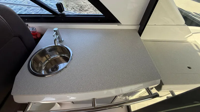 Slide: The Image of Cockpit Wet Bar with Sink This image showcases the sleek cockpit wet bar of the 2014 Regal 46 Sport Coupe, featuring a polished stainless steel sink set into a durable, easy-to-clean countertop. The bar is strategically positioned for easy access, enhancing the outdoor entertainme - 6857460