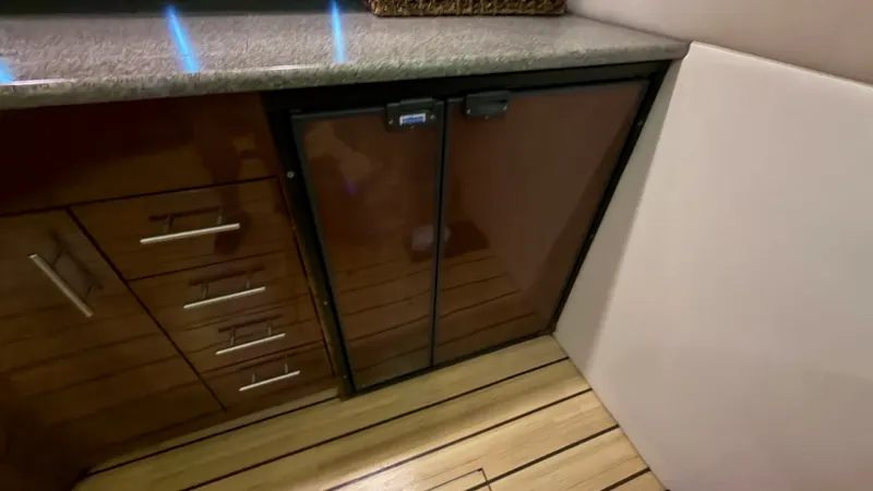 Slide: The Image of Galley with Refrigerator and Storage This image showcases the galley area of the 2014 Regal 46 Sport Coupe. The sleek cabinetry is complemented by a polished countertop, with a built-in refrigerator ensuring convenient access to refreshments. The warm wood tones and modern hardware add a tou - 6857431