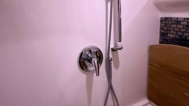 Slide: The Image of Luxurious Yacht Shower Area This image showcases the elegant shower area of the 2014 Regal 46 Sport Coupe. The space features a sleek chrome shower fixture and a modern handheld showerhead for versatile use. The combination of smooth white surfaces and textured wooden accents create - 6857442