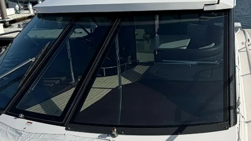 Slide: The Image of Helm Windshield and Hardtop View The image showcases the sleek windshield and sturdy hardtop of the Regal 46 Sport Coupe, Serenity in the Sea. The expansive glass provides excellent visibility from the helm, while the robust hardtop offers protection from the elements. This combination e - 6857473