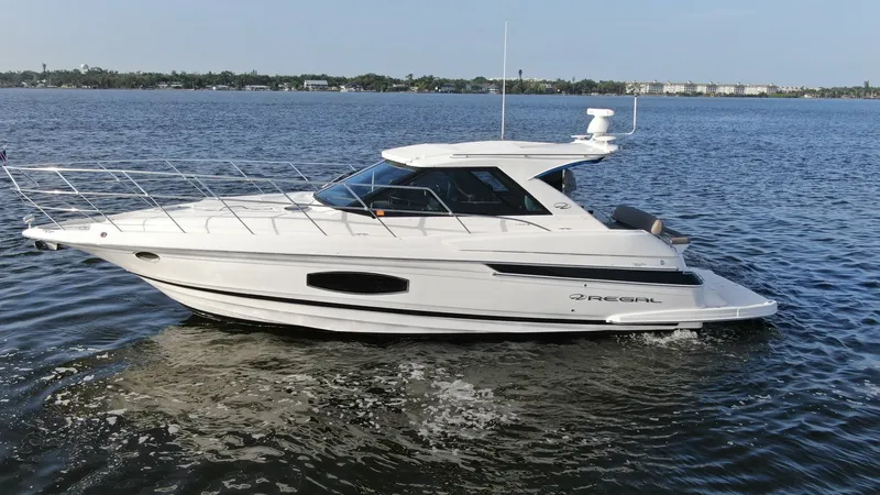 Slide: The Image of Side Profile of Regal 46 Sport Coupe This image showcases the sleek side profile of the 2014 Regal 46 Sport Coupe, Serenity in the Sea. The vessel's elegant lines and aerodynamic design are highlighted against a serene water backdrop. Featuring a spacious deck and modern hardtop, this yacht - 6857482