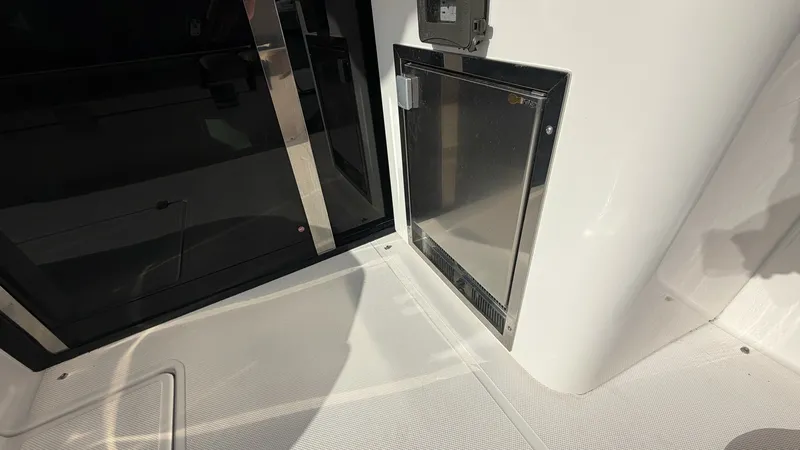 Slide: The Image of Cockpit Wet Bar and Storage Area This image showcases the sleek and functional wet bar area in the cockpit of the 2014 Regal 46 Sport Coupe. Featuring a compact fridge with a modern stainless steel finish, this space is perfect for entertaining guests. The surrounding cabinetry offers am - 6857463