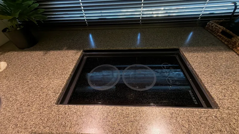 Slide: The Image of Galley with Electric Cooktop This image showcases the sleek, modern galley of the 2014 Regal 46 Sport Coupe. Featuring a polished granite countertop, the area is equipped with a Kenyon electric cooktop, perfect for gourmet meal preparation. The ambient lighting and window blinds add - 6857433