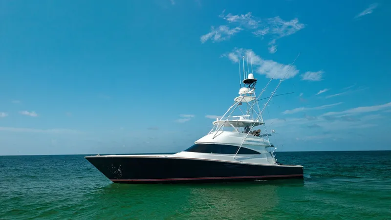 Slide: The Image of Side Profile of Viking 68 Convertible The Viking 68 Convertible presents a sleek and powerful profile against a clear blue sky and tranquil sea. This 2022 model, named Tax Man, exhibits the hallmark craftsmanship of Viking with its streamlined hull and towering flybridge. The elegant curvatur - 7463835