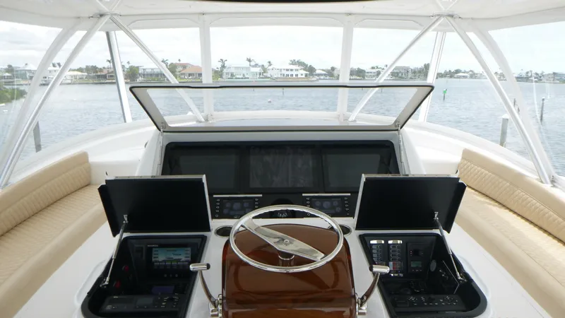 Slide: The Image of Flybridge Helm Station with Electronics The flybridge helm station of the 2022 Viking 68 Convertible showcases a sleek, modern design with state-of-the-art electronics. Dual consoles with advanced navigation and control systems flank a polished wooden steering wheel, providing a sophisticated c - 6862358