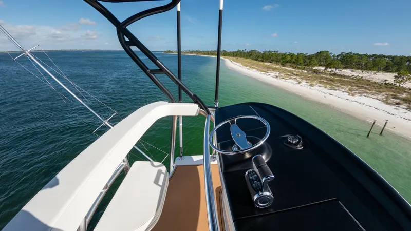 Slide: The Image of Flybridge Helm with Ocean View The flybridge of the 2022 Viking 68 Convertible offers a commanding view of the ocean and shoreline. Featuring a sleek helm with state-of-the-art controls, this area ensures smooth navigation and comfort. The open layout and elevated seating provide an id - 7463827