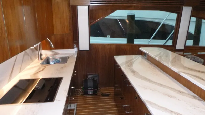 Slide: The Image of Galley The galley of the 2022 Viking 68 Convertible showcases elegant countertops paired with rich walnut cabinetry. This space is equipped with a modern cooktop and sink, providing both functionality and style. Large windows enhance the area with natural light, - 6862334