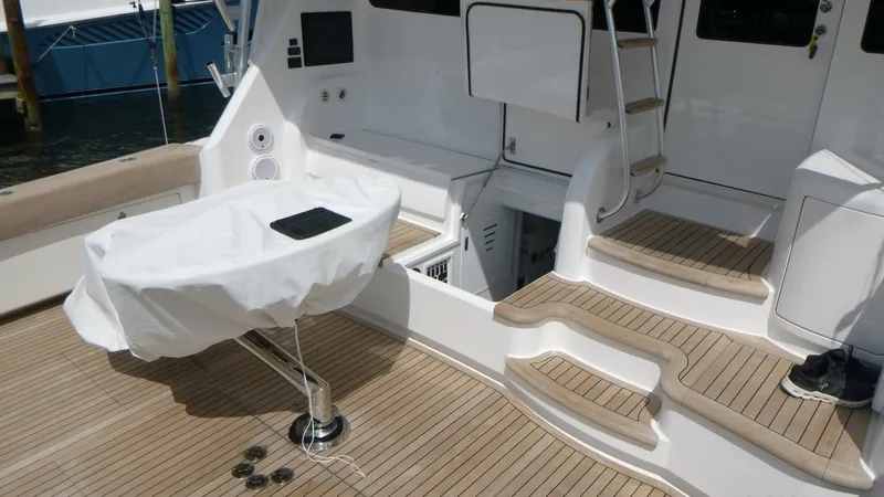 Slide: The Image of Cockpit The aft deck of the 2022 Viking 68 Convertible features elegant teak sole, providing a luxurious and durable surface. This area is equipped with a covered table and spacious seating, perfect for outdoor relaxation or dining. The well-designed steps lead t - 6862327