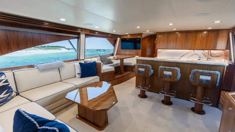 Slide: The Image of Salon and Galley with Island Bar The spacious salon of the 2022 Viking 68 Convertible features elegant wood finishes and plush seating, creating a warm and inviting atmosphere. Large windows provide panoramic views and ample natural light, enhancing the luxurious feel. The galley boasts - 7463798