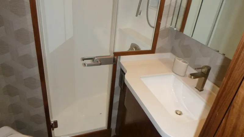 Slide: The Image of Master Head This luxurious ensuite bathroom on the 2022 Viking 68 Convertible features a modern design with high-end finishes. The sleek sink and vanity are complemented by a stylish faucet and ample counter space. The glass-enclosed shower adds a touch of sophistica - 6862340