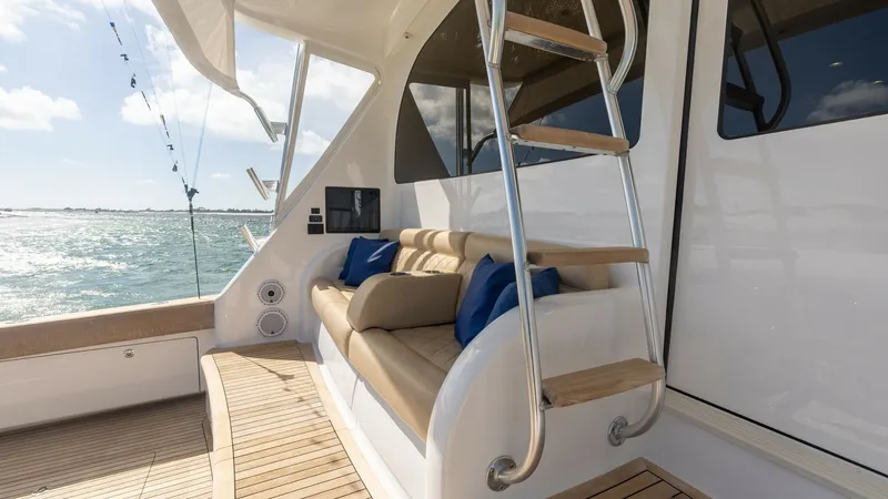 Slide: The Image of Aft Deck with Seating and Ladder The aft deck of the 2022 Viking 68 Convertible showcases a comfortable seating area with plush cushions and accent pillows, perfect for relaxation while enjoying the sea views. The teak decking adds a touch of elegance, and the ladder provides easy access - 7463794