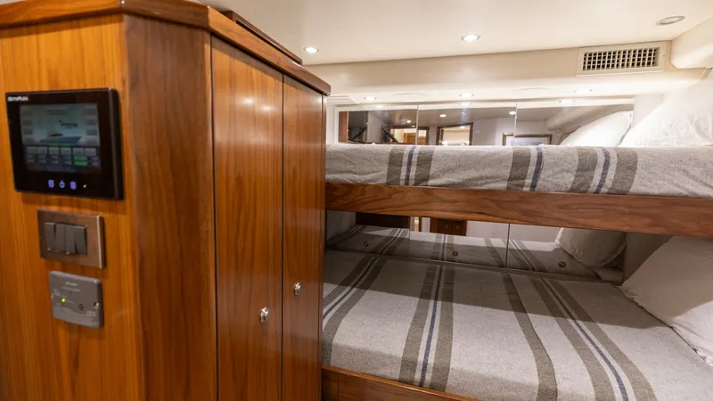 Slide: The Image of Crew Stateroom with Bunk Beds This inviting crew stateroom features comfortable bunk beds with plush striped bedding, providing ample sleeping space for guests. The warm wood cabinetry adds a touch of elegance, complemented by modern lighting and ventilation for a cozy atmosphere. A c - 7463820