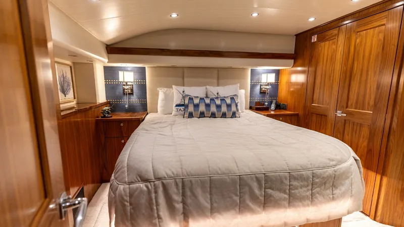 Slide: The Image of Luxurious Master Stateroom The master stateroom of the 2022 Viking 68 Convertible offers a blend of elegance and comfort. Featuring a plush queen-sized bed, surrounded by rich wood cabinetry and soft ambient lighting, this space exudes luxury. Ample storage and sophisticated decor - 7463808