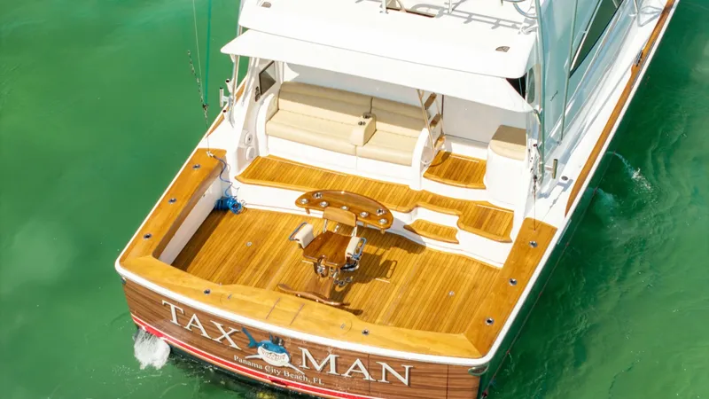 Slide: The Image of Aft Deck with Teak Finish The aft deck of the 2022 Viking 68 Convertible, 'Tax Man', showcases a beautifully crafted teak finish. This space is perfect for fishing or lounging, featuring a central fighting chair and cushioned seating. The area is designed for both functionality an - 7463830