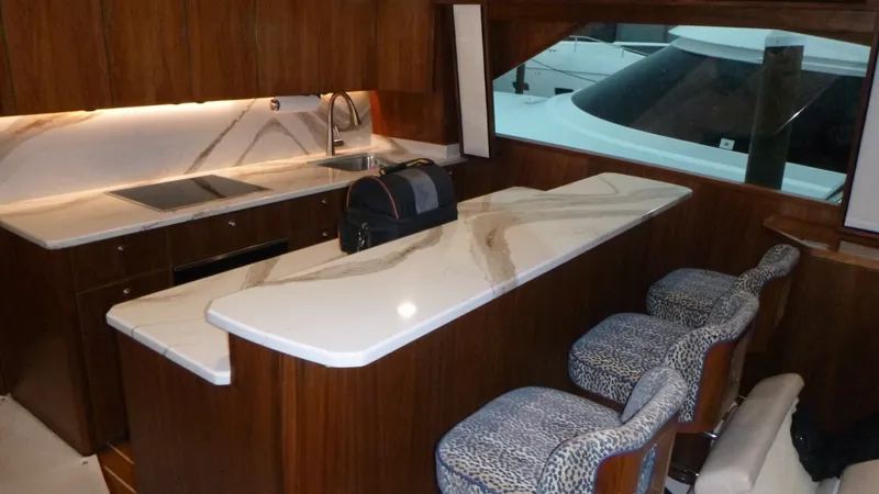 Slide: The Image of Galley The galley of the 2022 Viking 68 Convertible features a sleek countertop, providing a luxurious and functional space for meal preparation. Rich walnut cabinetry offers ample storage, complemented by modern appliances. The stylish bar stools add a touch of - 6862323