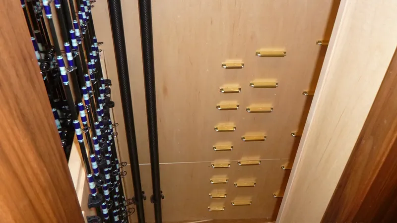 Slide: The Image of Custom Rod Storage Locker This image showcases the custom rod storage locker aboard the 2022 Viking 68 Convertible. The storage area is designed with precision, featuring secure mounts for multiple fishing rods, ensuring they are kept organized and safe while at sea. The wood fini - 6862332
