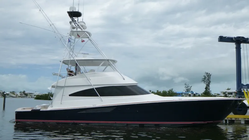 The Image of Profile View of Viking 68 Convertible This image showcases the sleek and powerful profile of the 2022 Viking 68 Convertible, 'Tax Man'. The boat features a striking dark hull and a spacious flybridge, equipped with a robust tower for optimal sportfishing capabilities. The elegant design and m - 6862321