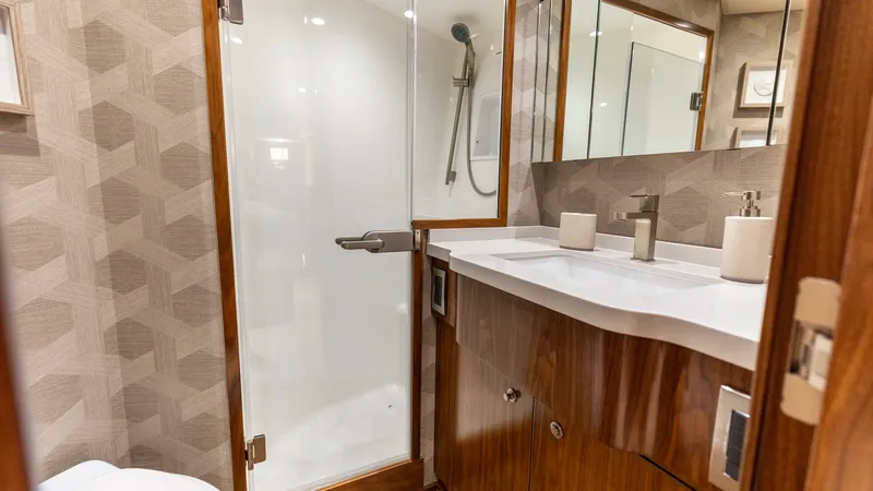 Slide: The Image of Elegant Ensuite Bathroom This ensuite bathroom features a sleek glass shower enclosure and modern fixtures, creating a luxurious retreat on the Viking 68 Convertible. Rich wood cabinetry and a polished countertop offer ample storage and style. The geometric wall pattern adds a to - 7463811