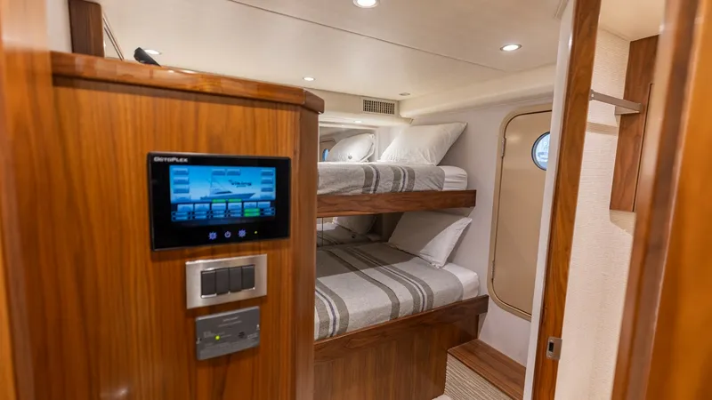 Slide: The Image of Crew Cabin with Bunk Beds The crew cabin features stylish bunk beds with plush bedding, offering comfort and space efficiency. The warm wood finishes and soft lighting create an inviting atmosphere. A digital Octoplex control panel enhances convenience, providing easy access to in - 7463819