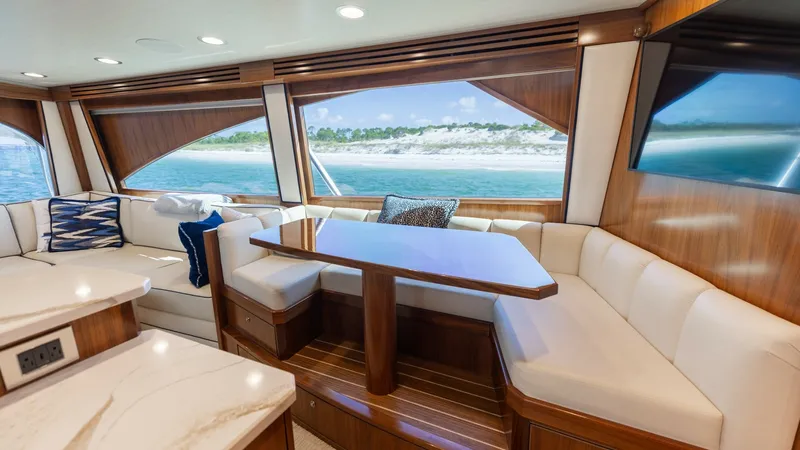 Slide: The Image of Salon with Panoramic Windows The salon of the Viking 68 Convertible offers luxurious seating with plush, cream-colored upholstery and a beautifully crafted wooden table. Expansive panoramic windows provide stunning views of the ocean, enhancing the spacious feel of the interior. The - 7463802