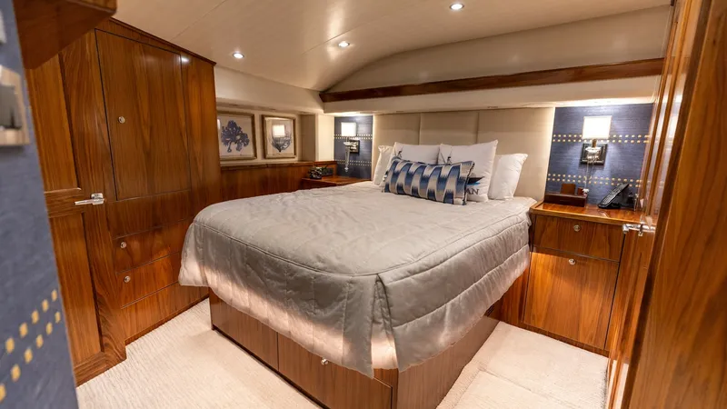 Slide: The Image of Luxurious Master Stateroom This master stateroom on the Viking 68 Convertible offers a blend of elegance and comfort with its rich wood finishes and plush bedding. The room features ample cabinetry for storage and stylish wall sconces that enhance the warm ambiance. A spacious layo - 7463789