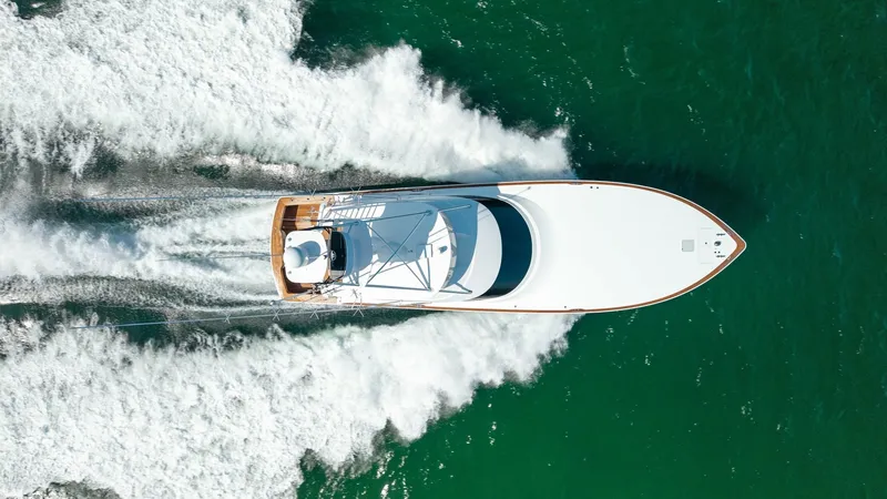 Slide: The Image of Aerial View of Yacht in Motion This aerial shot captures the sleek design of the 2022 Viking 68 Convertible, 'Tax Man,' cutting through the water with precision. The vessel's streamlined hull and expansive foredeck highlight its superior craftsmanship. The wake trailing behind showcase - 7463839