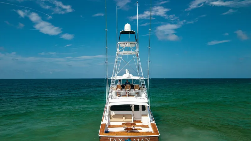 Slide: The Image of Aft View with Tower and Cockpit This striking view of the 2022 Viking 68 Convertible, 'Tax Man', showcases its impressive aft deck and towering tuna tower. The spacious cockpit is designed for serious fishing, with ample seating and a clear view of the open sea. The elegant teak decking - 7463833