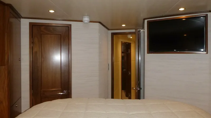 Slide: The Image of Master Stateroom Interior with TV The master stateroom on the Viking 68 Convertible features a warm wood finish and soft, ambient lighting. A flat-screen TV is mounted on the wall, offering entertainment and convenience. The comfortable bedding and elegant door details enhance the invitin - 6862337