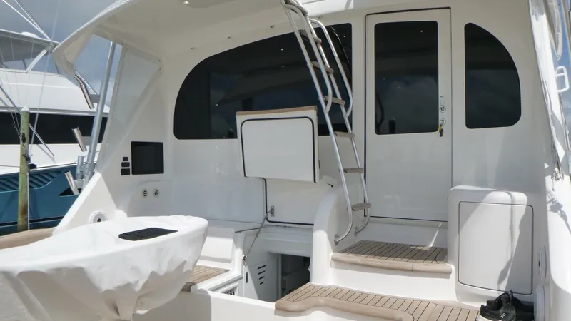 Slide: The Image of Cockpit The aft deck of the 2022 Viking 68 Convertible features a spacious cockpit with teak steps leading to the main salon entry. Its clean design includes a covered storage area, integrated grab rails, and a ladder to the flybridge. The layout is perfect for b - 6862325