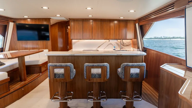 Slide: The Image of Galley with Bar Seating This elegant galley features a stylish bar with three cushioned stools, perfect for entertaining. The space is enhanced by rich wood cabinetry, modern appliances, and ample natural light from large side windows. The sleek design and open layout provide a - 7463801