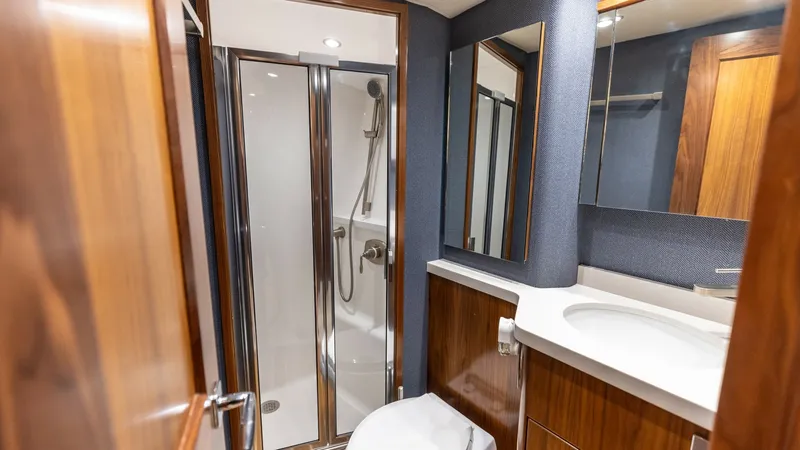 Slide: The Image of Elegant En-Suite Bathroom This luxurious en-suite bathroom on the Viking 68 Convertible features a modern glass-enclosed shower and sleek fixtures. The rich wood cabinetry and polished countertops add a touch of elegance, while the ample mirror enhances the space. Designed for com - 7463818