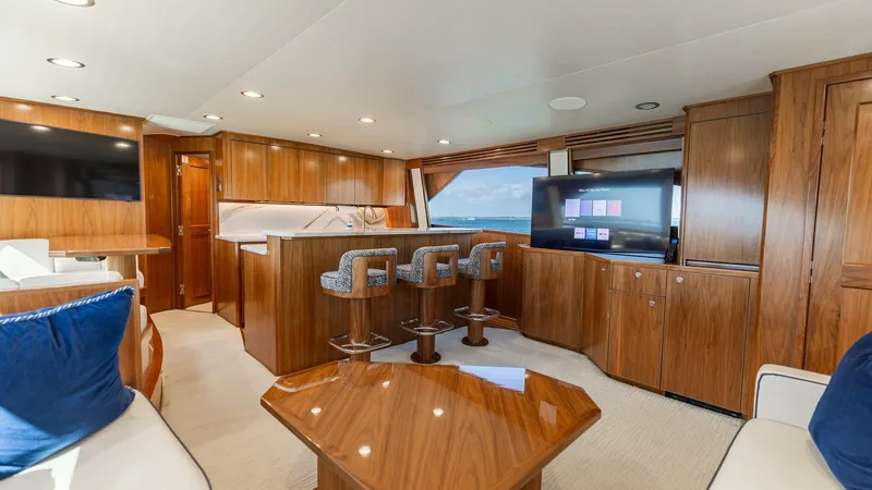 Slide: The Image of Luxurious Salon with Open Galley This spacious salon aboard the 2022 Viking 68 Convertible showcases a beautifully designed open galley and entertainment area. Rich wood cabinetry complements the sleek countertops, while plush seating and a large flat-screen TV offer relaxation and conve - 7463806
