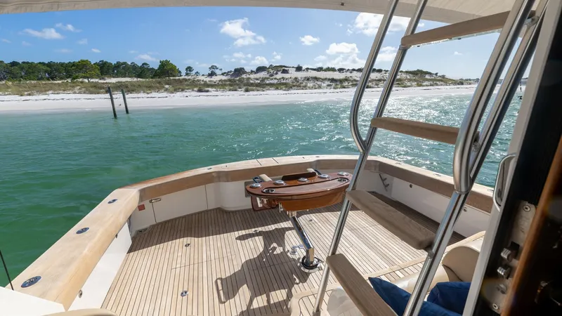 Slide: The Image of Spacious Aft Deck with Seating The aft deck of the 2022 Viking 68 Convertible offers a spacious and inviting area for relaxation and fishing. Featuring elegant teak flooring and a center-mounted fighting chair, this space is perfect for both leisure and sport. The stainless-steel ladde - 7463793