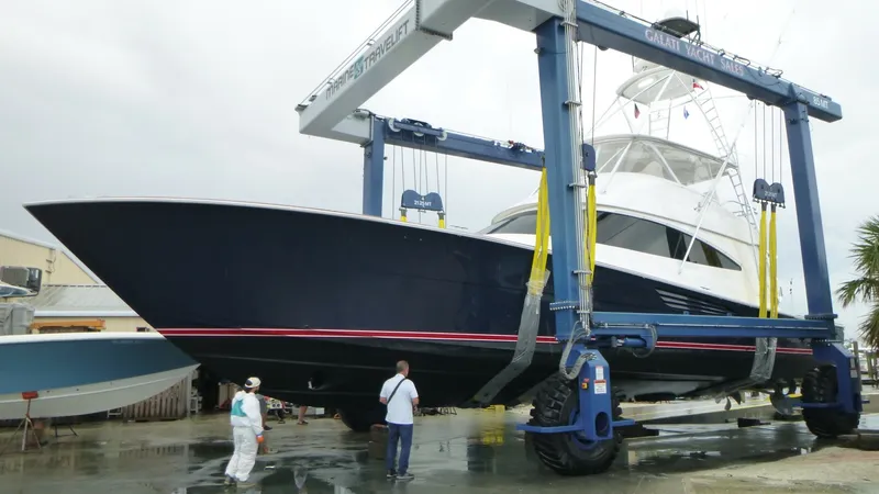 Slide: The Image of Viking 68 Convertible in Shipyard Lift The Viking 68 Convertible 'Tax Man' is seen here in a shipyard lift, showcasing its sleek hull design and robust construction. The dark blue hull with red accents highlights its elegant profile, while the spacious flybridge is visible above. This image ca - 6862370