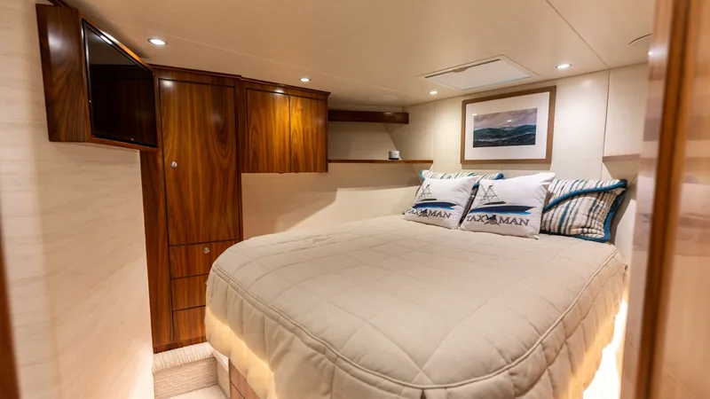 Slide: The Image of Elegant Forward Stateroom with Rich Wood Accents This stateroom aboard the 2022 Viking 68 Convertible exudes luxury and comfort. Featuring a plush, centrally positioned bed adorned with custom pillows, the room showcases rich wood cabinetry offering ample storage. Soft ambient lighting and tasteful artw - 7463813